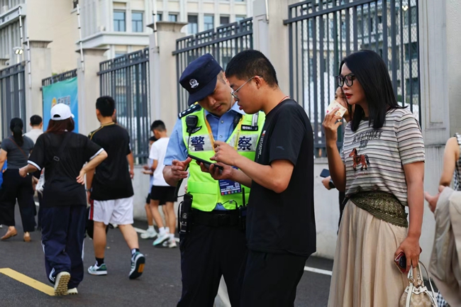 长汀县公安局巡特警反恐大队教导员刘胜平在长汀万人体育场外围入口为球迷指路。林丽莎摄