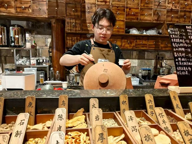“草本堂”中药奶茶店主理人高凌旭在熬制中药奶茶。傅俊杰摄