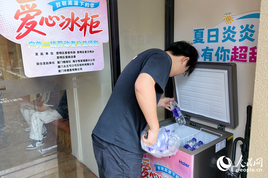 在曾厝垵街区，一家民宿的工作人员往“爱心冰柜”中存放瓶装饮用水。人民网记者 陈博摄