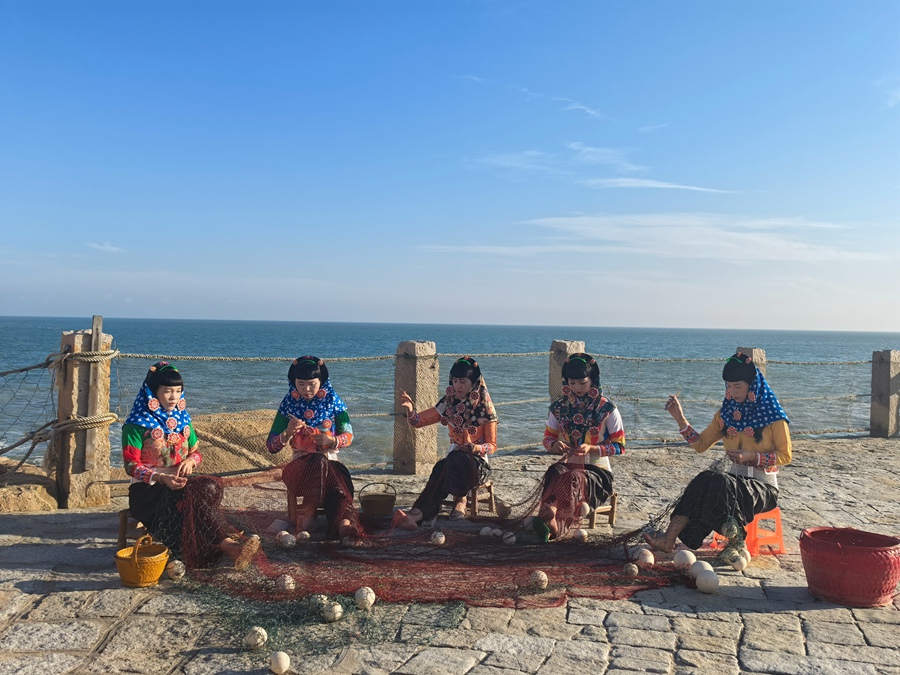 身着传统服饰的惠安女在海边补渔网。刘晓宇摄