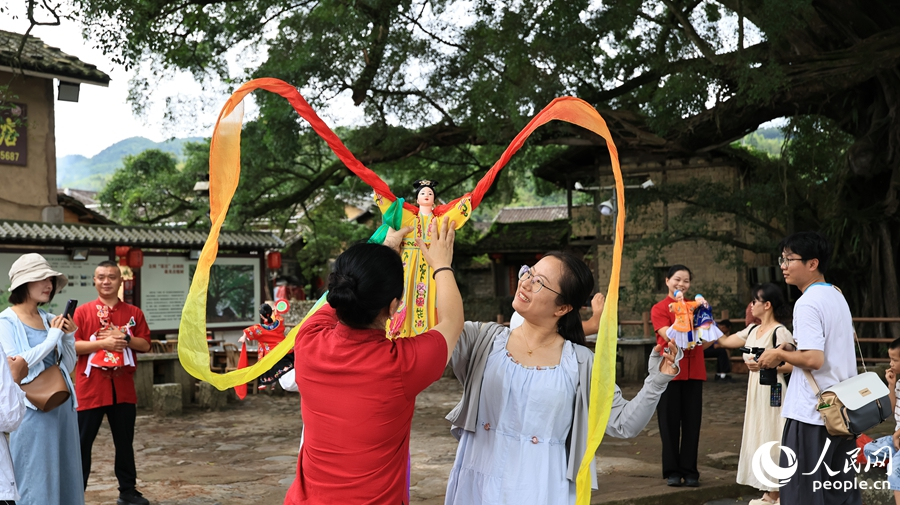 游客在福建土楼（南靖）旅游景区体验漳州布袋木偶戏表演。人民网记者 李昌乾摄