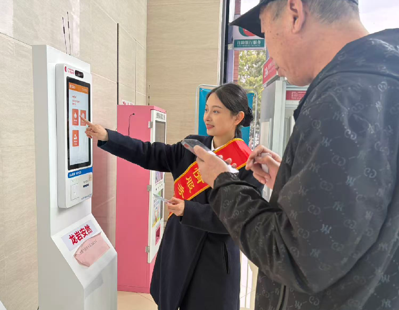 工作人员指引办事群众通过自助服务设备办理业务