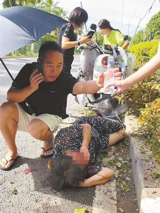 鄧彥撥打報警電話並撐起雨傘為受傷女子遮陽。另外兩位熱心女士也一起幫忙。視頻截圖