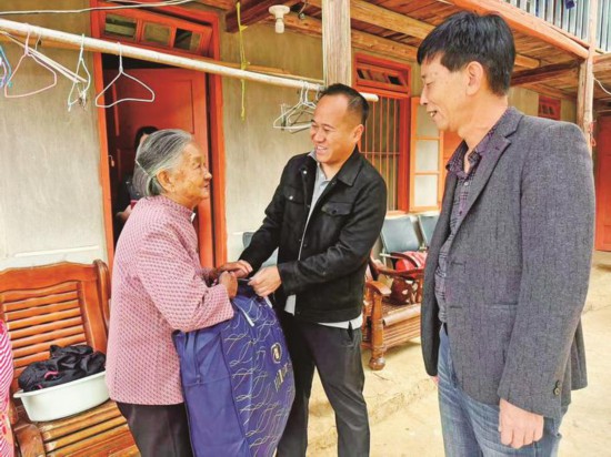 周桂平(中)为高龄老人送去冬被。